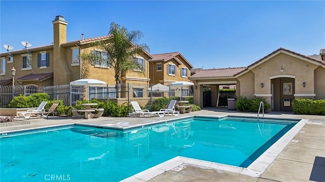 community pool with fence and a patio