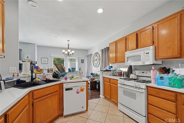kitchen featuring an inviting chandelier, a peninsula, white appliances, a sink, and light tile patterned floors