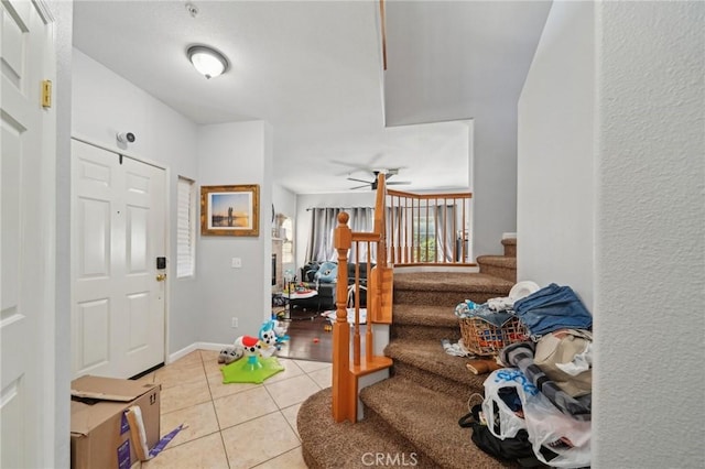 foyer entrance with tile patterned flooring, a ceiling fan, and stairs