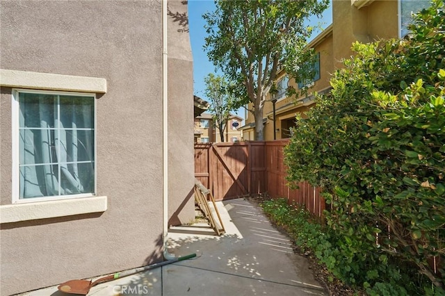 view of side of home featuring fence, a patio area, and stucco siding