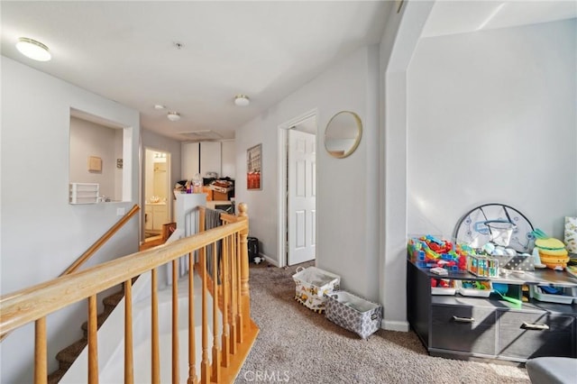 hall with baseboards, carpet, and an upstairs landing