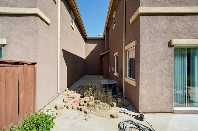 view of home's exterior with fence, a patio, stucco siding, and central AC
