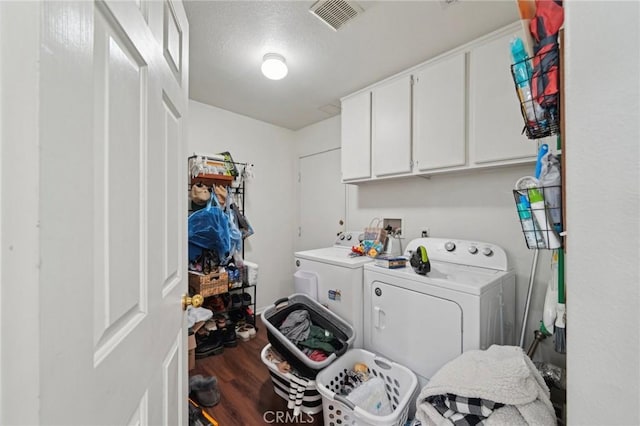 washroom with cabinet space, visible vents, washer and clothes dryer, and wood finished floors