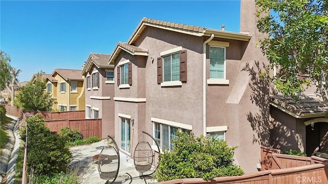 view of home's exterior with stucco siding, a patio area, fence, and a tiled roof