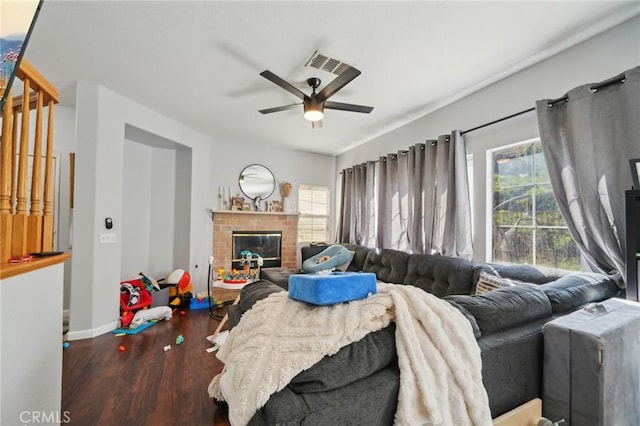 living room featuring ceiling fan, a fireplace, baseboards, wood finished floors, and visible vents