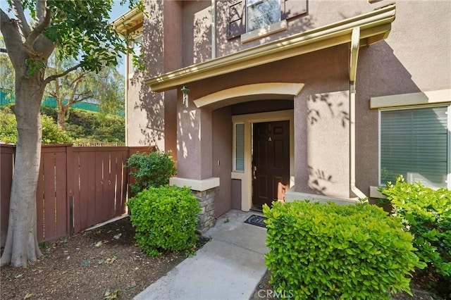 property entrance with fence and stucco siding