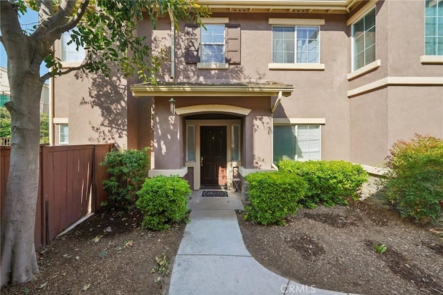property entrance with fence and stucco siding