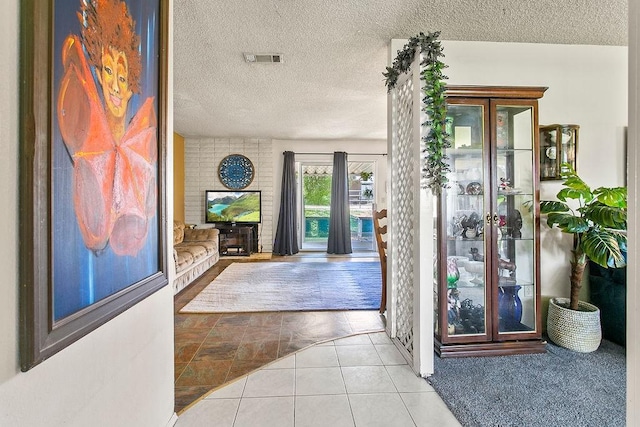 tiled foyer entrance featuring visible vents and a textured ceiling