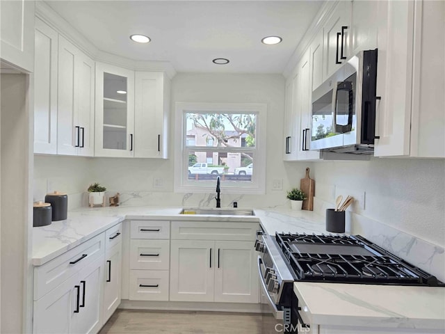 8611 Chapman Ave, Garden Grove, CA 92841 - kitchen with stainless steel appliances, a sink, white cabinets, light stone countertops, and recessed lighting