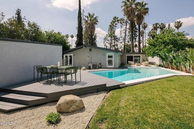 view of pool featuring a lawn, a deck, a fenced in pool, and outdoor dining space