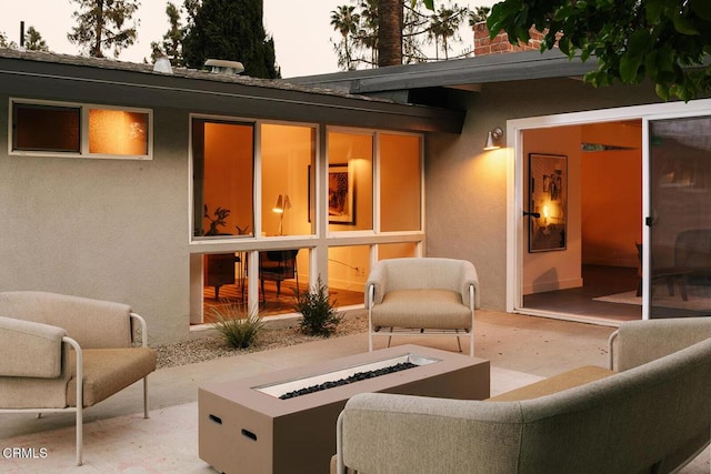 back of property featuring a patio, an outdoor living space with a fire pit, and stucco siding