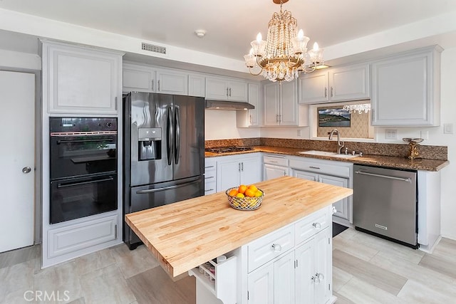 kitchen with stainless steel dishwasher, dobule oven black, gas cooktop, fridge with ice dispenser, and a sink