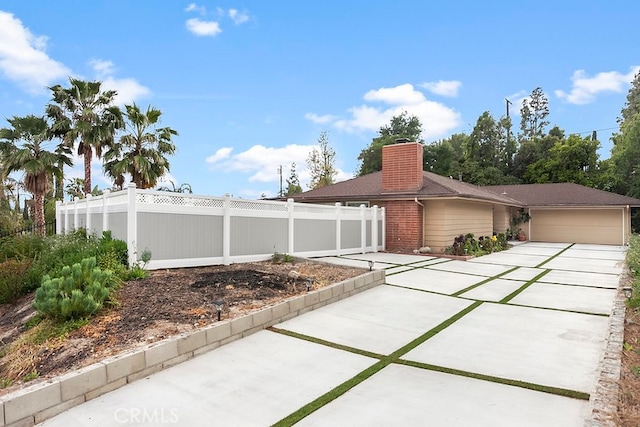 exterior space with fence private yard, an attached garage, driveway, and a chimney
