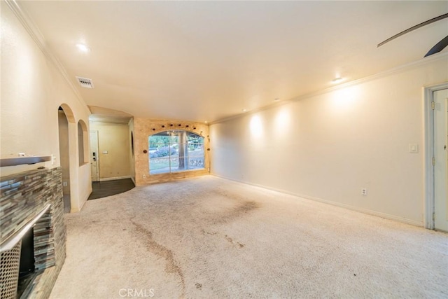 unfurnished living room with visible vents, arched walkways, crown molding, and carpet floors