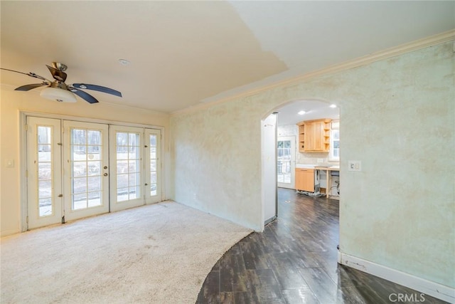 unfurnished room featuring crown molding, a ceiling fan, dark wood-type flooring, french doors, and arched walkways