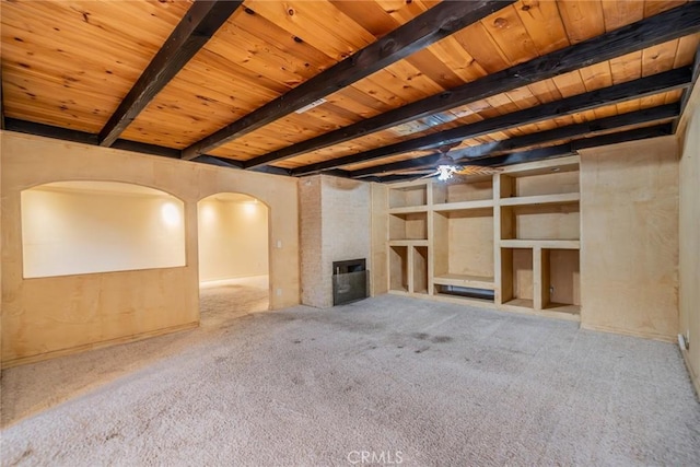 unfurnished living room with wood ceiling, beamed ceiling, arched walkways, and carpet floors