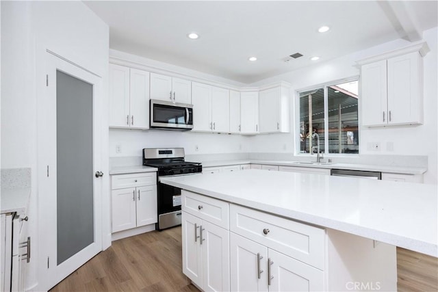347 Beckes St, Wasco, CA 93280 - kitchen featuring appliances with stainless steel finishes, a sink, light countertops, white cabinets, and light wood-style flooring