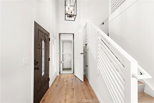 foyer entrance featuring light wood-style floors, a high ceiling, and a chandelier
