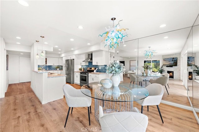 dining room featuring light wood-style floors, recessed lighting, a chandelier, and a fireplace