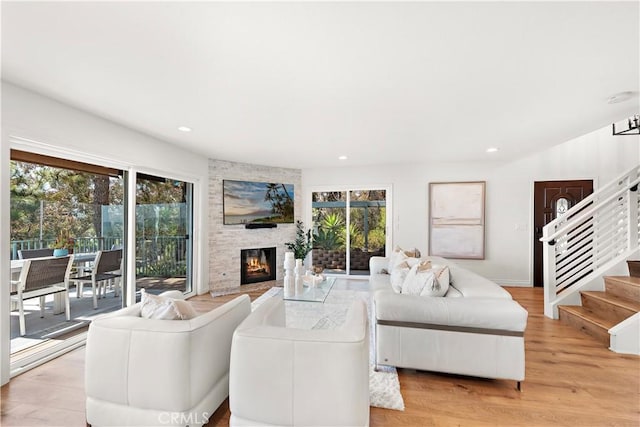 living area featuring recessed lighting, a wealth of natural light, stairway, and a fireplace
