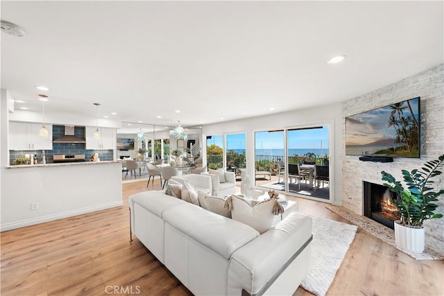 living room featuring light wood-style floors, recessed lighting, and a stone fireplace