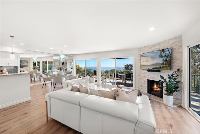 living area with light wood-style floors, ceiling fan, a fireplace, and recessed lighting