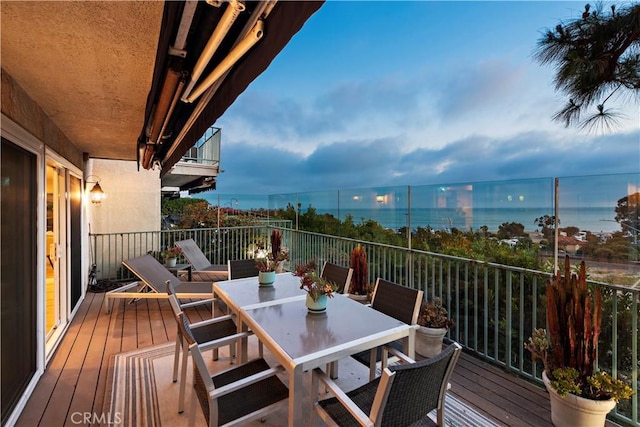 wooden terrace with a water view and outdoor dining space