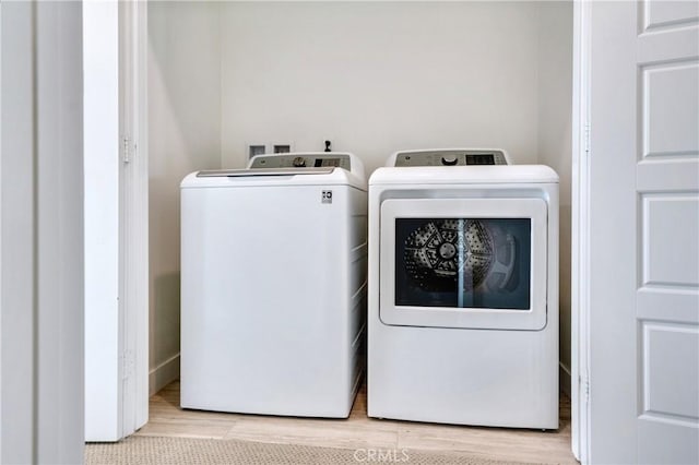 clothes washing area featuring laundry area, washing machine and dryer, and wood finished floors