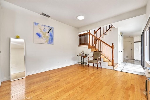 interior space featuring baseboards, visible vents, light wood-style flooring, and stairway