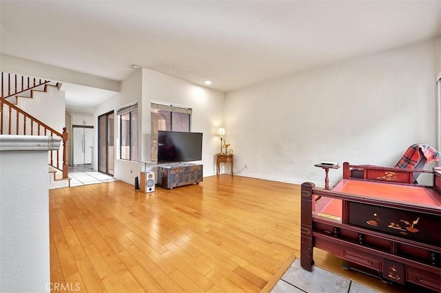 living area featuring stairway, baseboards, and wood finished floors