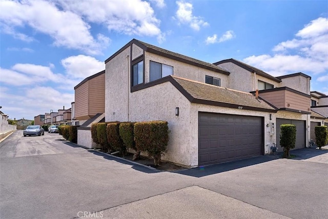 view of front of house featuring aphalt driveway, stucco siding, and a residential view