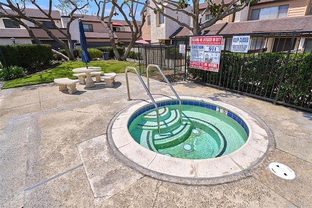 view of swimming pool with a community hot tub, fence, and a residential view