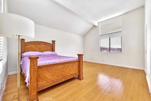 bedroom with baseboards, vaulted ceiling with beams, and light wood finished floors