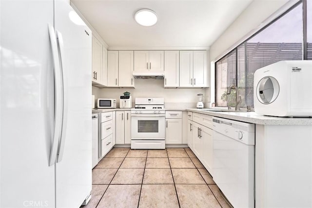 kitchen featuring white appliances, light countertops, white cabinetry, under cabinet range hood, and a sink