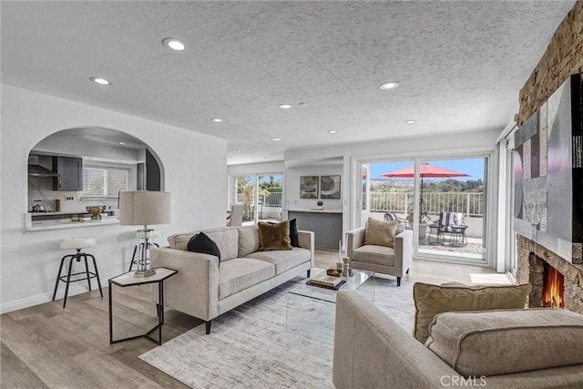 3118 Calle Grande, San Clemente, CA 92672 - living room with recessed lighting, a textured ceiling, light wood finished floors, arched walkways, and a large fireplace