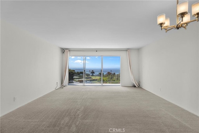 carpeted spare room featuring a notable chandelier