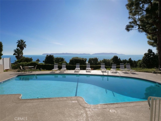 community pool with a water view and a patio area