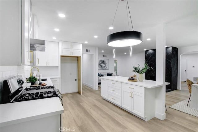 kitchen featuring under cabinet range hood, light wood finished floors, and white cabinetry