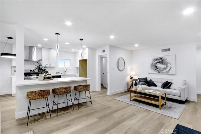 living room with recessed lighting, baseboards, visible vents, and light wood-style flooring