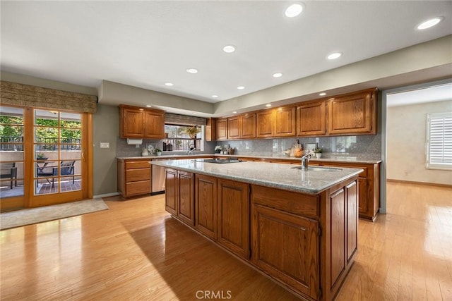 112 Morgan Ranch Rd, Glendora, CA 91741 - kitchen featuring brown cabinets, a sink, baseboards, light wood-style flooring, and an island with sink