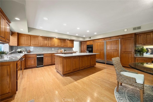 112 Morgan Ranch Rd, Glendora, CA 91741 - kitchen with a kitchen island with sink, oven, light wood-style floors, brown cabinets, and a sink