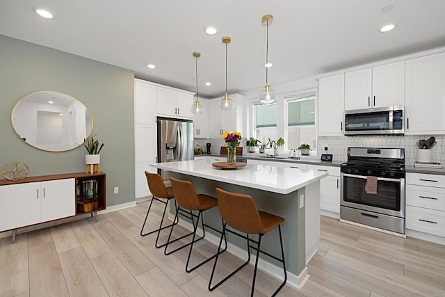 10456 Newbliss Way, Mira Mesa, CA 92126 - kitchen featuring stainless steel appliances, a breakfast bar area, tasteful backsplash, a center island, and light wood-type flooring