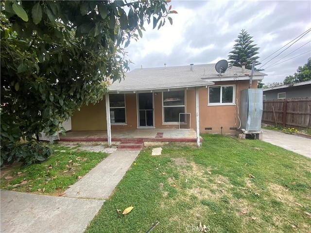 view of front of property with fence, covered porch, stucco siding, a shingled roof, and a front lawn
