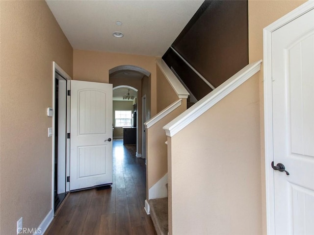 corridor with arched walkways, recessed lighting, baseboards, dark wood-style floors, and stairway