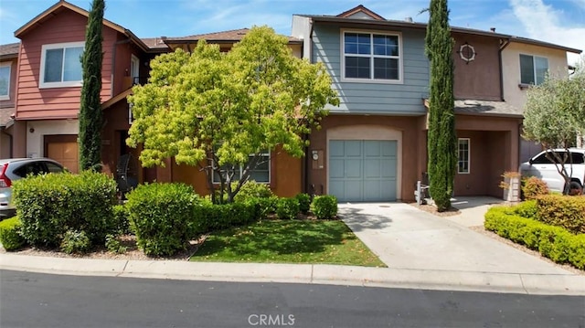 townhome / multi-family property with a garage, stucco siding, and concrete driveway