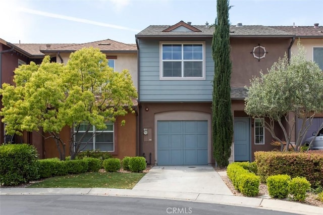 multi unit property featuring an attached garage, stucco siding, and driveway