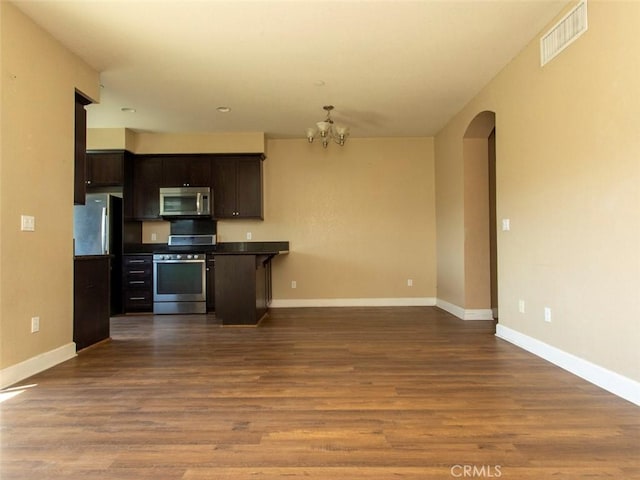 kitchen with an inviting chandelier, arched walkways, stainless steel appliances, open floor plan, and visible vents