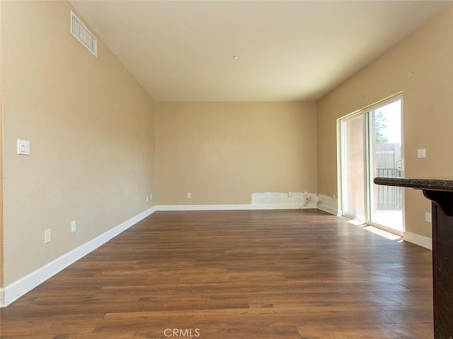 unfurnished living room with baseboards, dark wood finished floors, and visible vents