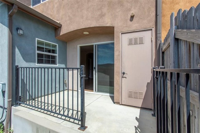 doorway to property featuring visible vents and stucco siding