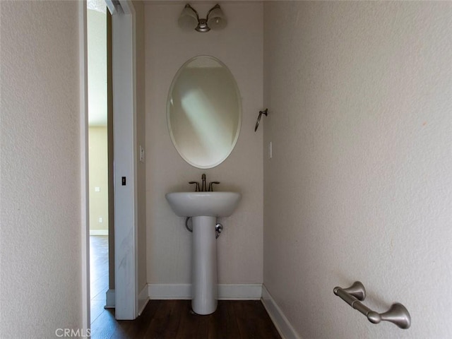 bathroom with a sink, baseboards, and wood finished floors